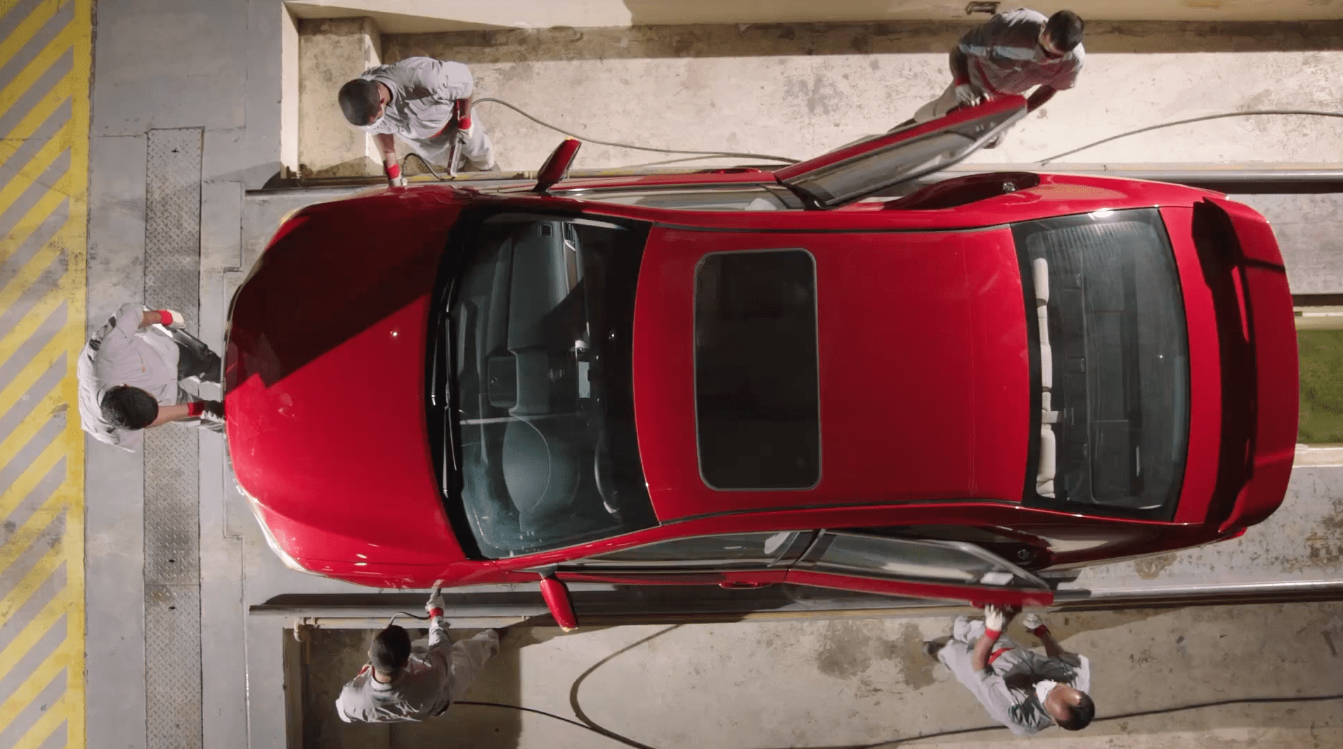 Top view of a red car servicing by 4 employees of Saud Bahwan